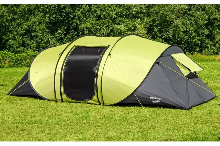 Grünes Tunnelzelt auf Gras mit Bäumen im Hintergrund