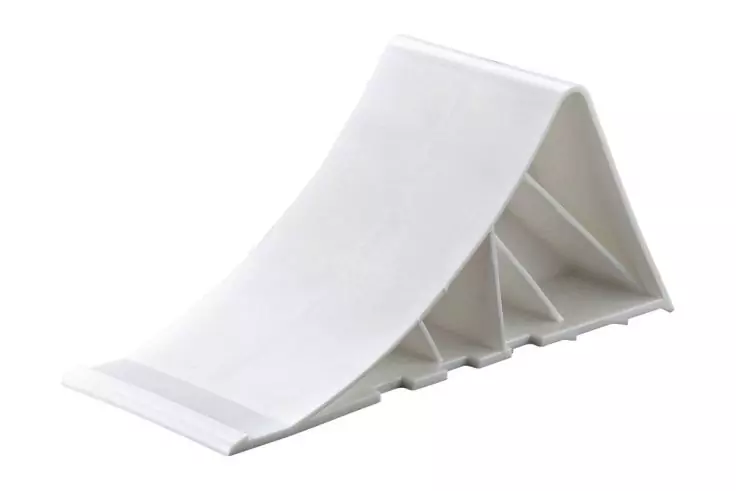 Weißes keilförmiges Kunststoffobjekt mit dreieckigen Hohlräumen und leicht gebogener Oberseite auf weißem Hintergrund
