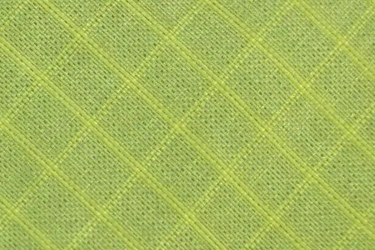 Nahaufnahme eines grünen Stoffs mit diagonalem Rautenmuster und sichtbarer Webstruktur