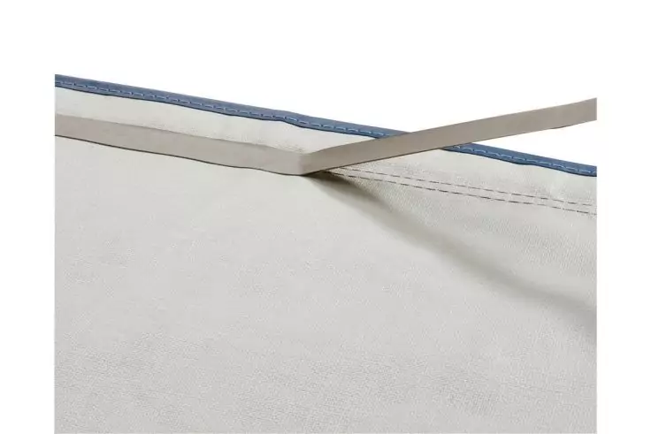 Helles Stofftuch mit sichtbarer Naht am oberen Rand, blauem Einfassstreifen, zwei überkreuzten dünnen Stäben und Schatten auf dem Stoff