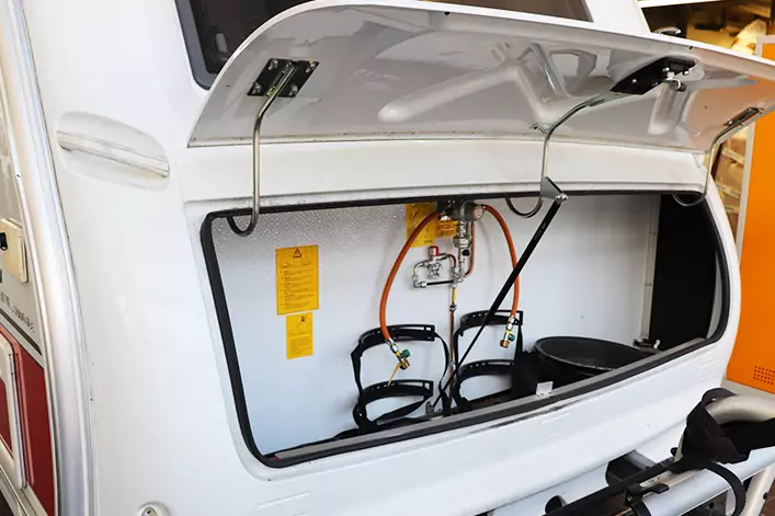 Geöffneter Außenstaukasten eines Wohnmobils mit zwei Gasflaschen, Schläuchen und Druckregler