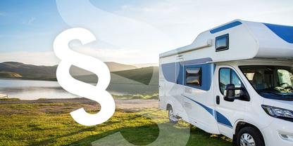 Wei&szlig;es Wohnmobil auf Gras neben einem See, gro&szlig;es wei&szlig;es Paragrafenzeichen im Vordergrund, H&uuml;gel und bew&ouml;lkter Himmel im Hintergrund