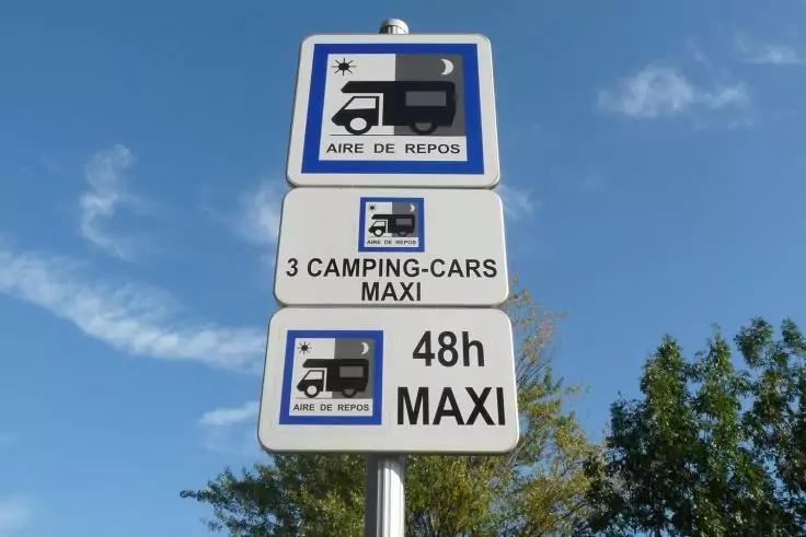 Drei Verkehrsschilder an einem Mast mit Wohnmobil-Piktogrammen und den Texten 'AIRE DE REPOS', '3 CAMPING-CARS MAXI' und '48h MAXI' vor blauem Himmel