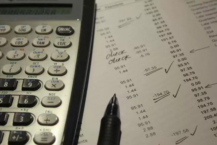 Taschenrechner links, Kugelschreiber auf einem Blatt mit gedruckten Zahlen, handschriftlichen Markierungen und H&auml;kchen