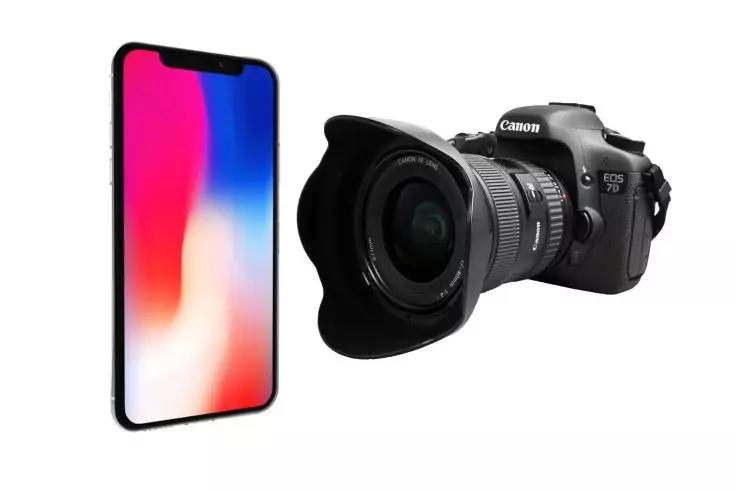 Smartphone mit buntem Display links und schwarze DSLR-Kamera mit gro&szlig;em Objektiv rechts auf wei&szlig;em Hintergrund