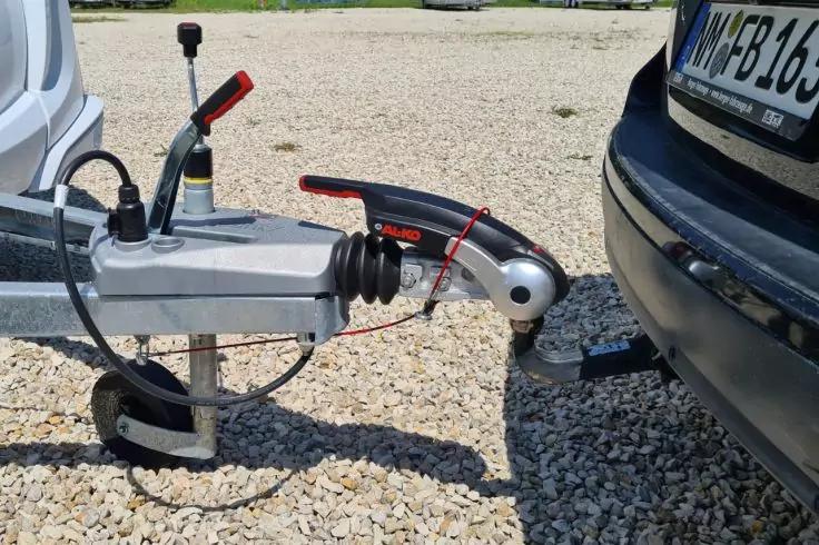 Anh&auml;nger-Kupplung auf der Anh&auml;ngerkupplung eines Autos, sichtbarer Sto&szlig;f&auml;nger und Kiesboden