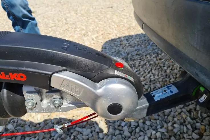 Anh&auml;ngekupplung und Kugelkopf eines Fahrzeugs, rotes Kabel, Kiesuntergrund, Teil der Fahrzeugsto&szlig;stange