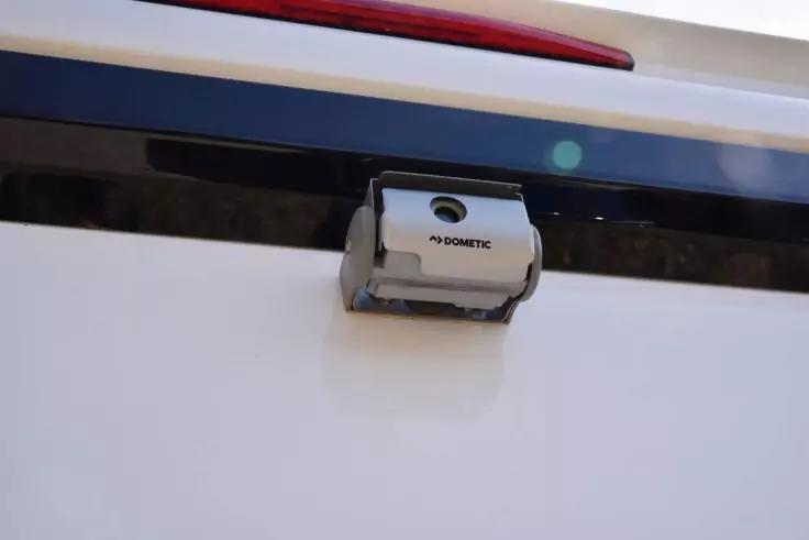 Wei&szlig;e Fl&auml;che mit einem grauen, rechteckigen Ger&auml;t mit der Aufschrift DOMETIC und einer runden Linse, montiert unter einer roten Reflektorleiste