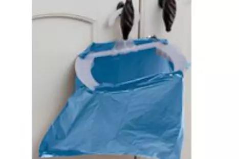 Blaue Plastikt&uuml;te h&auml;ngt &uuml;ber einem hellen T&uuml;rgriff; zwei schwarze, gedrehte Gegenst&auml;nde h&auml;ngen oben an der T&uuml;r