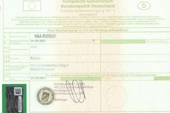 Formularseite mit gr&uuml;nem Rahmen, gedruckten Tabellenfeldern, Stempel, rundem Siegel, handschriftlicher Unterschrift und kleinem Aufkleber mit QR-Code unten links