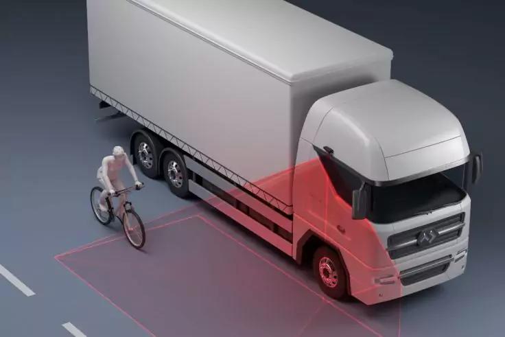 Wei&szlig;er Lastwagen auf der Stra&szlig;e, eine Person auf einem Fahrrad neben der Fahrzeugseite, rote halbtransparente Fl&auml;chen auf der Fahrbahn und entlang der Fahrerkabine