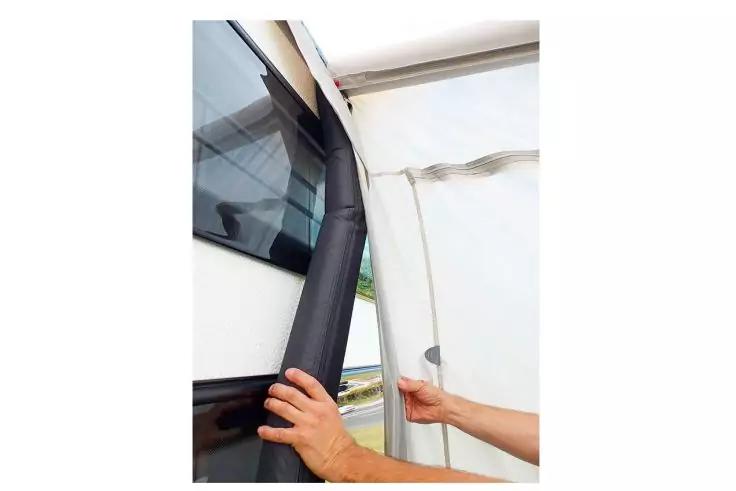 Zwei H&auml;nde halten einen schwarzen Gummistreifen zwischen wei&szlig;er Plane und Fahrzeugseite mit Fenster