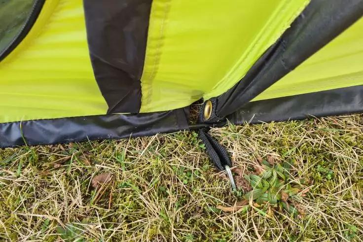 Gelb-schwarzer Stoff mit Metall&ouml;se, schwarzem Band und im Gras steckendem Metallpflock