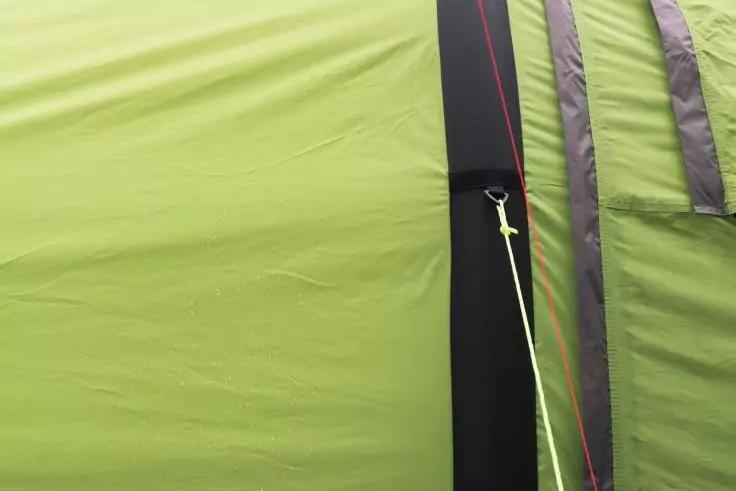 Nahaufnahme eines hellgr&uuml;nen Zeltstoffs mit vertikalem schwarzen Streifen, einer Metall&ouml;se und einer gelb-gr&uuml;nen Abspannleine