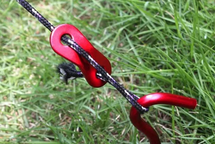 Zwei rote ovale Scheiben mit &Ouml;ffnungen, durch die eine schwarze Kordel verl&auml;uft, auf gr&uuml;nem Rasen