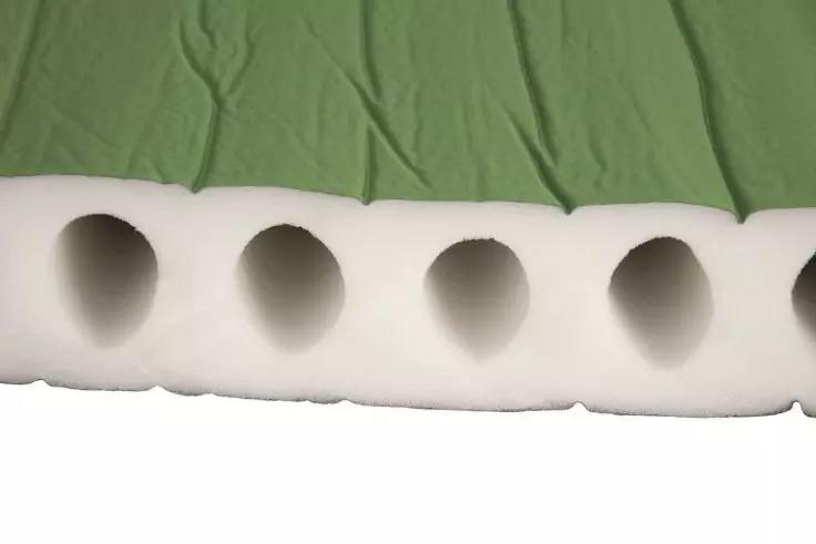 Wei&szlig;e Schaumstoffschicht mit f&uuml;nf gleichm&auml;&szlig;ig runden Aussparungen, dar&uuml;ber gr&uuml;ner Stoff