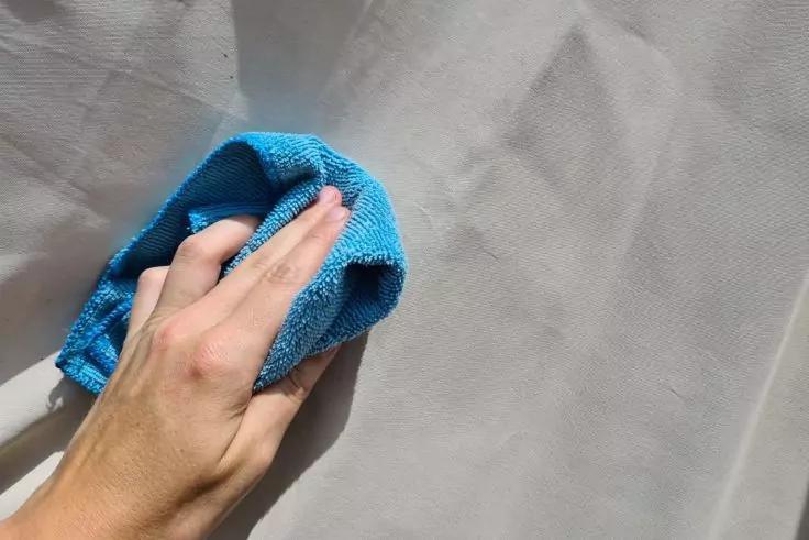 Zelthaut wird mit Tuch gereinigt.