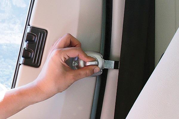 Hand hält silbernen Metallriegel/Schieber an der Innenseite eines Autotürrahmens, schwarze Gummidichtung, beige Innenverkleidung, Teil eines Fensters sichtbar