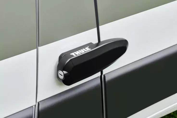 Schwarzes Thule-Gerät, über der Türfuge eines weißen Fahrzeugs befestigt