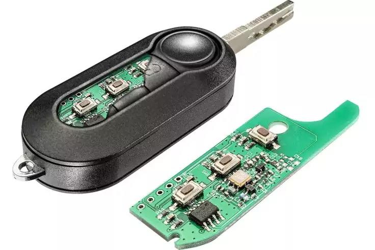Schwarzes Schlüsselgehäuse mit Metallbart und freigelegter grüner Leiterplatte, daneben ein separates grünes Platinenstück mit Tasten auf weißem Hintergrund