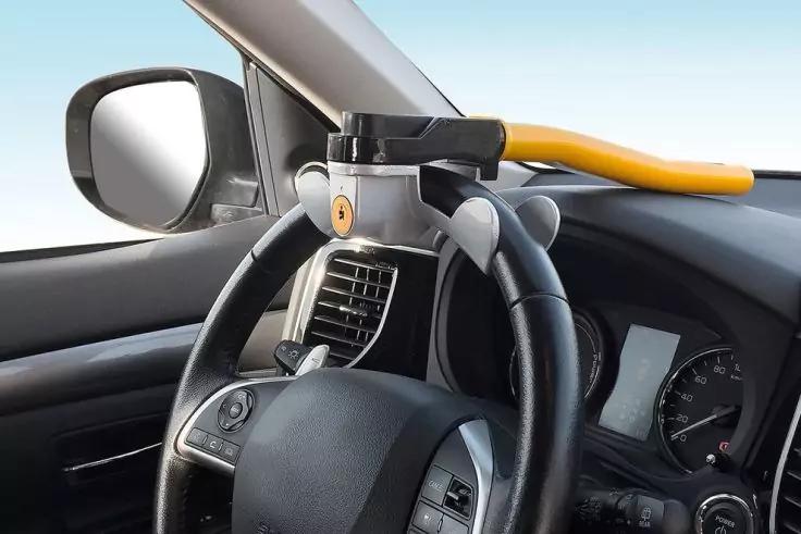 Autoinnenraum, Lenkrad mit befestigter Metallstange mit gelbem Griff, Armaturenbrett und Außenspiegel sichtbar