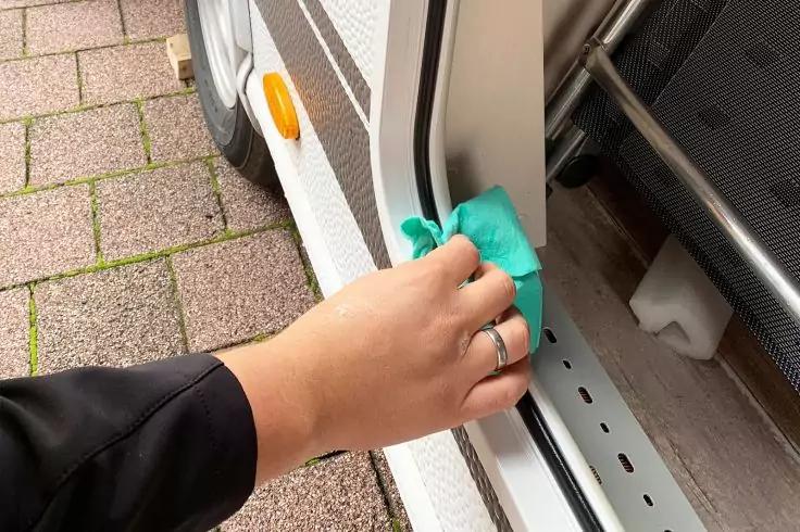 Hand mit Ring hält einen grünen Kunststoffhebel an der Türschwelle eines geöffneten Fahrzeugs