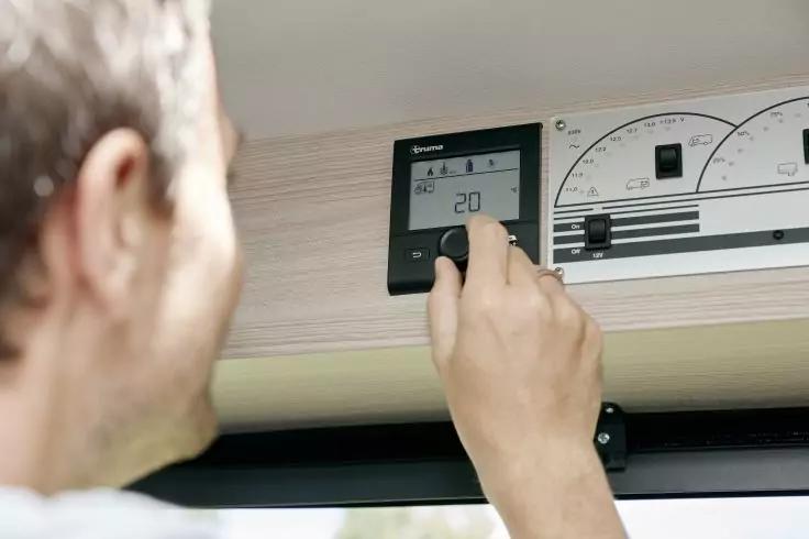 Person dreht an einem digitalen Regler; Display zeigt "20"; daneben ein analoges Messinstrument an einer Holzverkleidung