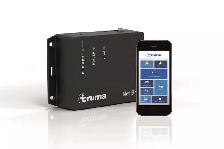 Schwarzes, rechteckiges Elektronikger&auml;t mit Aufdrucken 'truma' und 'iNet Box', daneben ein Smartphone mit blauem App-Bildschirm auf wei&szlig;em Hintergrund