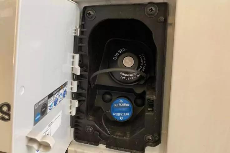 Offene Tankklappe eines Fahrzeugs mit zwei Einf&uuml;ll&ouml;ffnungen, schwarzer Deckel mit Aufschrift 'DIESEL' und blauer Deckel mit Aufschrift 'AdBlue'