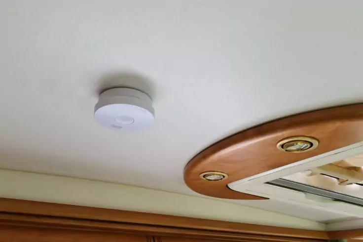 Rundes wei&szlig;es Ger&auml;t an einer hellen Decke, daneben ein Holzrahmen mit rechteckiger &Ouml;ffnung und drei runden Einbauleuchten