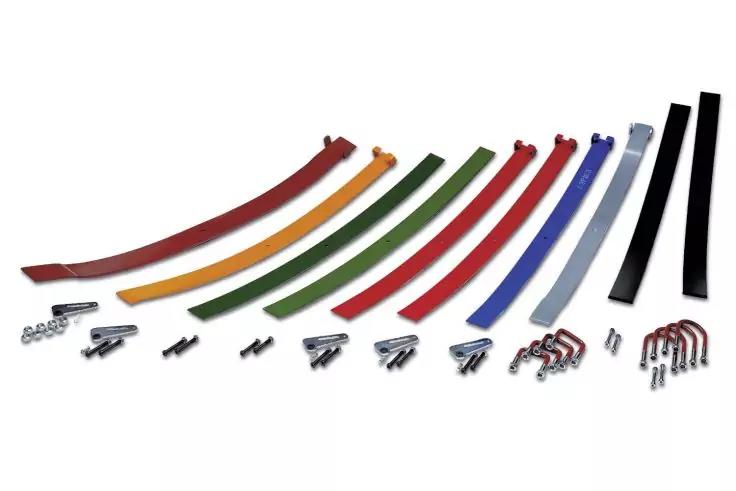 Mehrere gebogene Metallstreifen in verschiedenen Farben (rot, orange, gelb, gr&uuml;n, blau, schwarz) nebeneinander auf wei&szlig;em Hintergrund; vorne Schrauben, Muttern und U-B&uuml;gel