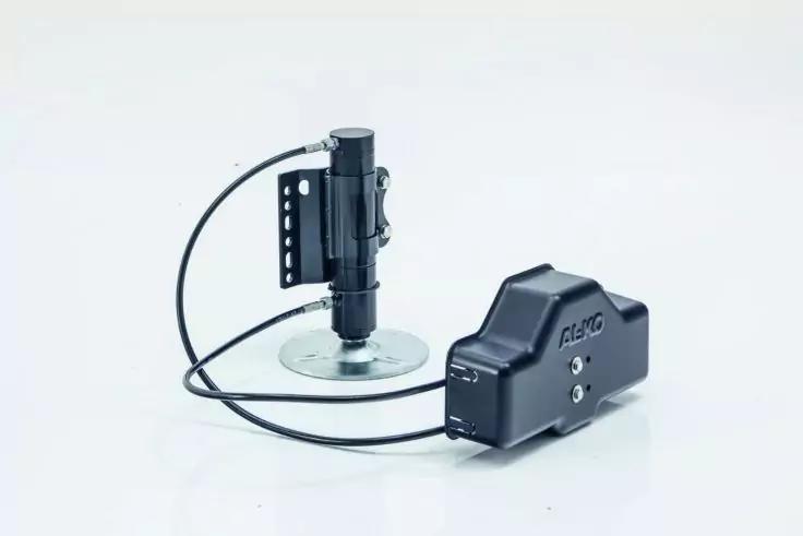 Schwarzes Ger&auml;t mit rundem Saugnapf, angeschlossenem Kabel und separatem schwarzen Geh&auml;use auf hellem Hintergrund