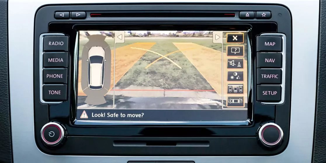Autoinfotainment-Bildschirm mit R&uuml;ckfahrkamera, Parklinien und dem Text "Look! Safe to move?"