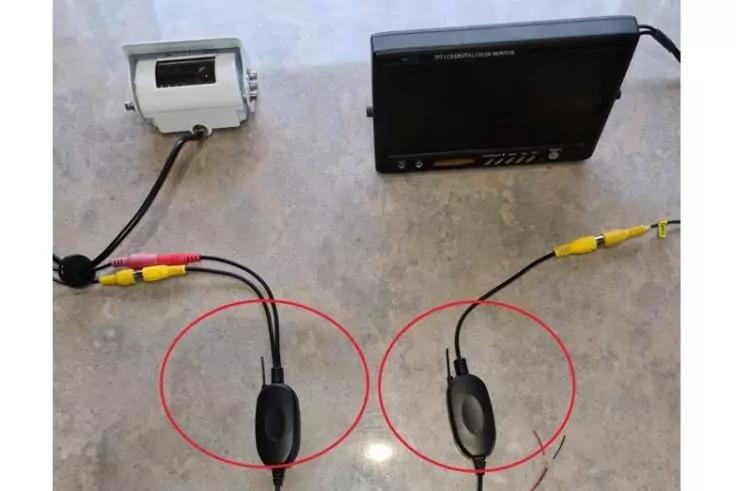 Zwei schwarze ovale Geräte mit Kabeln, rot umkreist, auf hellem Untergrund; oben links ein weißes Gerät, oben rechts ein schwarzer Monitor mit Kabeln und gelben Steckern