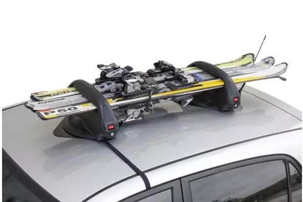 Silbernes Auto mit schwarzem Dachtr&auml;ger, darauf vier Skier mit Bindungen, Tr&auml;ger mit Riemen am Dach befestigt, Antenne sichtbar