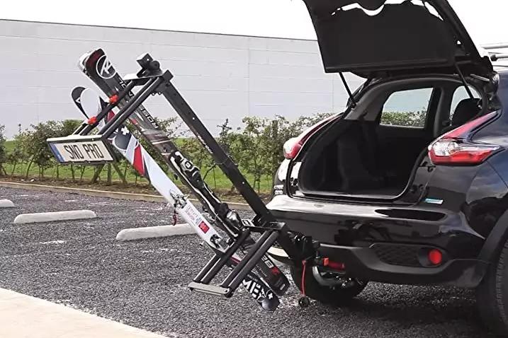 Schwarzer Kompaktwagen mit ge&ouml;ffnetem Kofferraum; an der Anh&auml;ngerkupplung montierter Fahrradtr&auml;ger mit zwei Fahrr&auml;dern, Parkplatz im Hintergrund