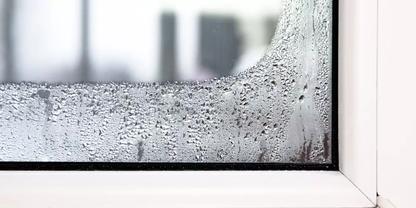 Wei&szlig;e Fensterecke mit Wassertropfen auf der Glasscheibe und unscharfer Au&szlig;enansicht