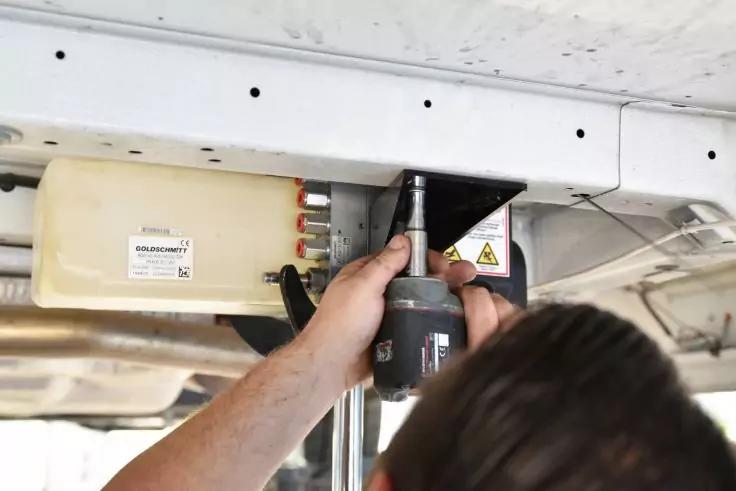 Person h&auml;lt elektrischen Schrauber und befestigt Metallwinkel an wei&szlig;er Unterseite; beige Kunststoffbox mit Anschl&uuml;ssen sichtbar