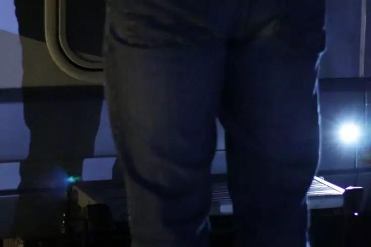 Untere K&ouml;rperh&auml;lfte einer stehenden Person in blauer Jeans, sichtbare H&uuml;fte und Beine, helles Licht und dunkler Hintergrund