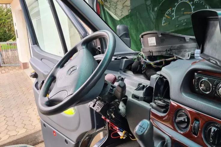 Innenraum einer Lkw-Fahrerkabine mit Lenkrad, Armaturenbrett, offenem Instrumententr&auml;ger mit sichtbaren Kabeln und Schalthebel