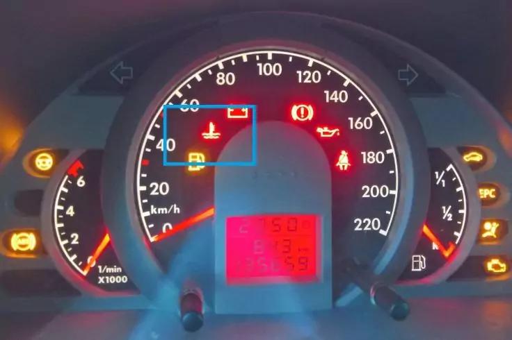 Armaturenbrett eines Autos mit beleuchtetem Tachometer und Drehzahlmesser, mehreren Warn- und Kontrollleuchten und einem roten digitalen Display