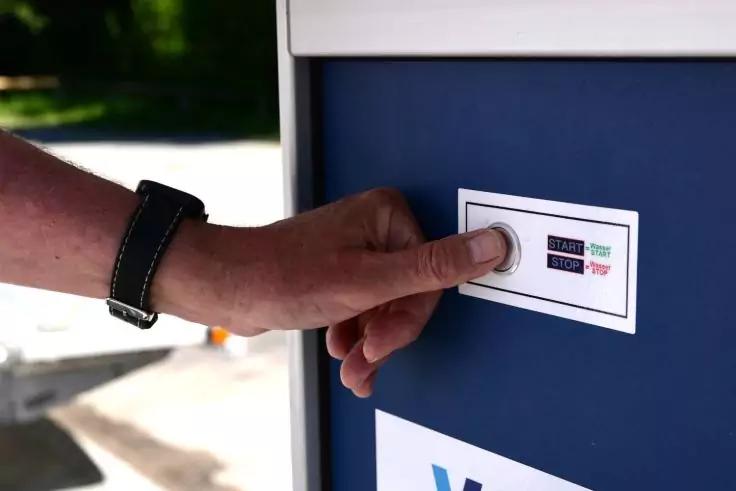 Hand dr&uuml;ckt runden Knopf auf wei&szlig;em Schild an blauem Kasten