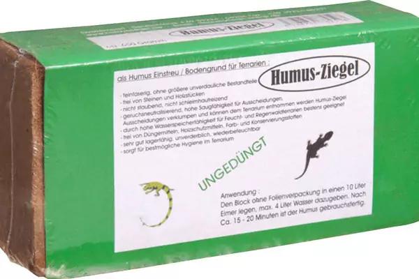 Gr&uuml;ner rechteckiger Karton mit wei&szlig;em Etikett 'Humus-Ziegel', bedrucktem Text und kleinen Pflanzenillustrationen