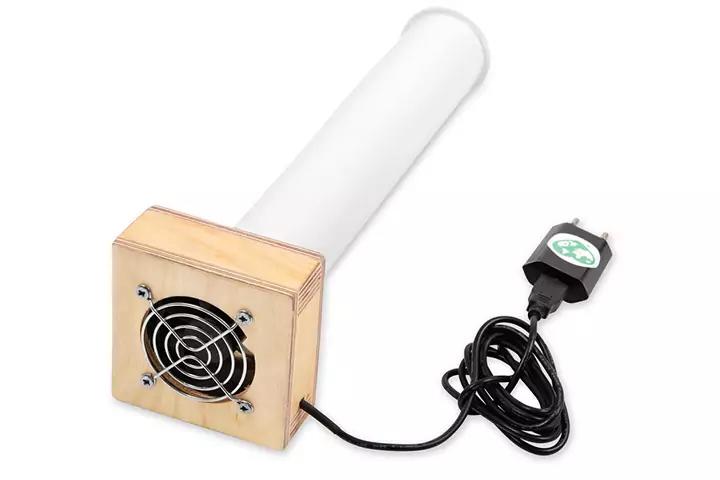 Wei&szlig;er zylindrischer Rohrk&ouml;rper, verbunden mit einem h&ouml;lzernen quadratischen Geh&auml;use mit sichtbarem Metalll&uuml;ftergitter; schwarzes Stromkabel mit Netzadapter, auf wei&szlig;em Hintergrund