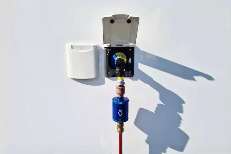 Wei&szlig;er Wandkasten mit offenem Deckel, schwarzer Einsatz, blau-gelbe Kupplung an rotem Schlauch, Schatten auf wei&szlig;er Wand