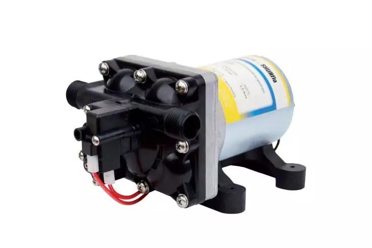 kleine elektrische Pumpe mit zylindrischem Geh&auml;use, schwarzer Anschlussplatte, zwei Schlauchanschl&uuml;ssen, sichtbaren Schrauben und roten sowie schwarzen Kabeln, auf zwei Standf&uuml;&szlig;en montiert