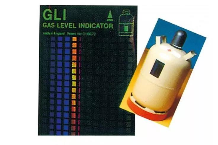 Rechts eine beige Gasflasche mit Ventil, links eine schwarze Karte mit der Aufschrift "GLI GAS LEVEL INDICATOR" und bunten Farbfeldern