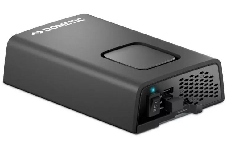 Appareil rectangulaire noir aux angles arrondis avec le logo Dometic dessus, dépression carrée sur le dessus, interrupteur marche/arrêt avec LED bleue sur un côté, prise ouverte avec port USB et grille d'aération