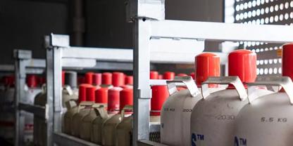 Reihen von Metallgasflaschen mit roten Verschl&uuml;ssen auf Regalen