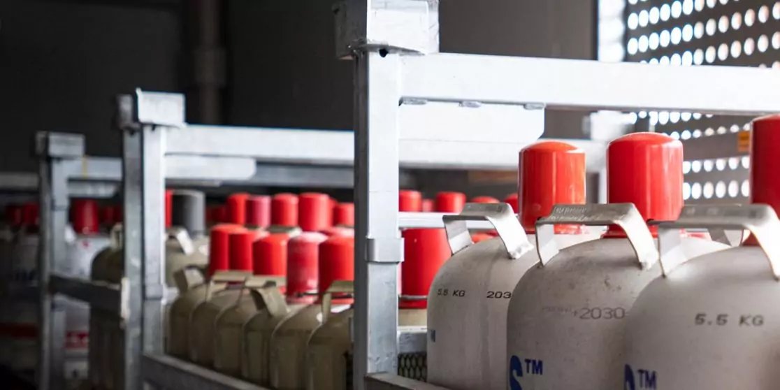 Reihen von Metallgasflaschen mit roten Verschl&uuml;ssen auf Regalen